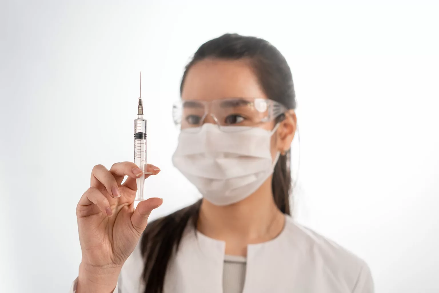 woman wearing a face mask holding a syringe