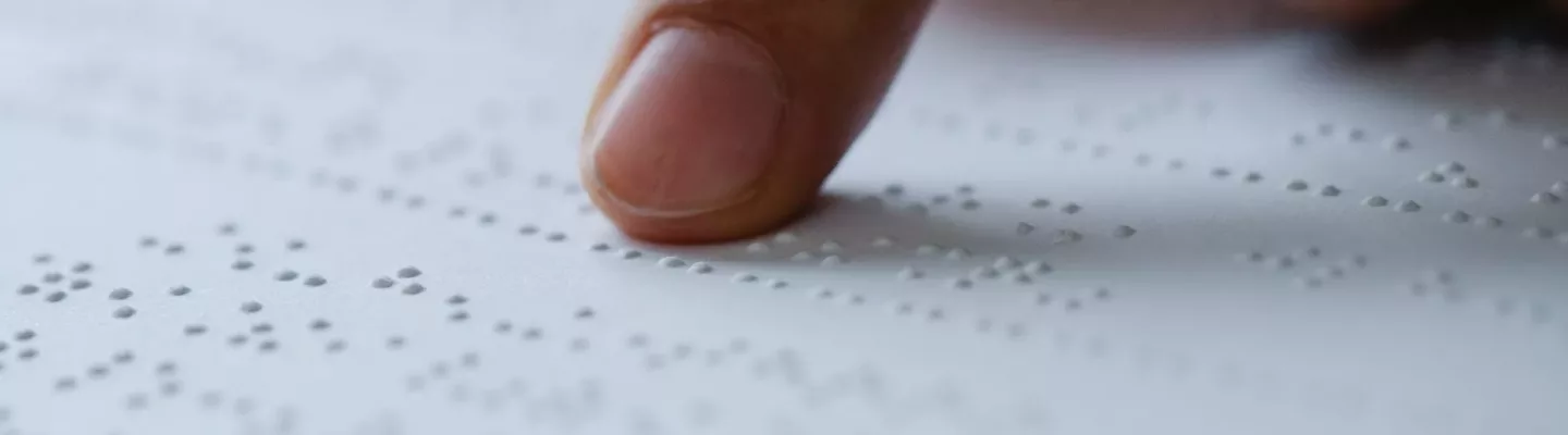 photo of person pointing on braille