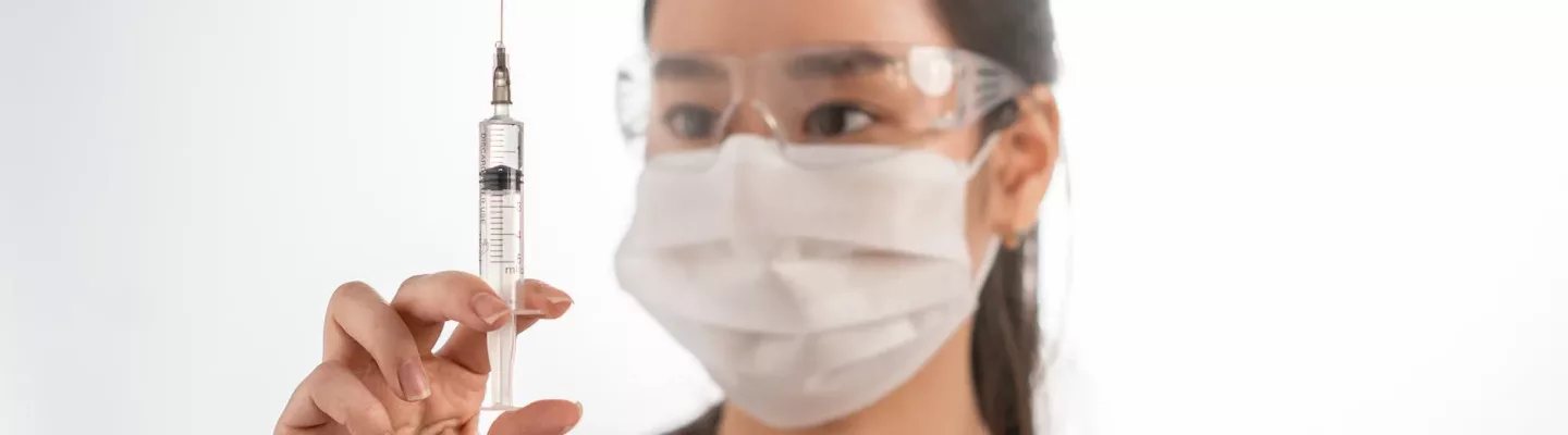 woman wearing a face mask holding a syringe